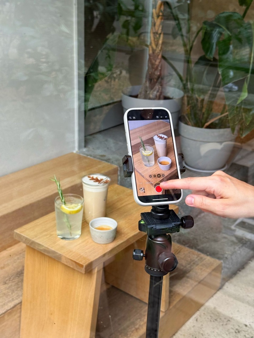 A phone on a tripod filming café drinks